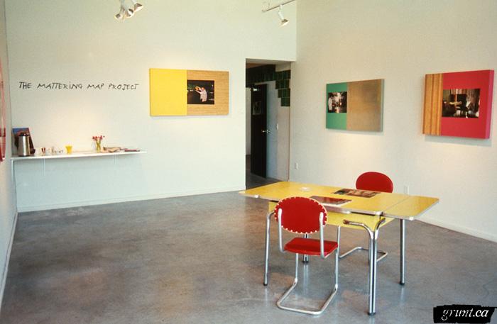 1996 06 04 The Mattering Map Project Pia Massie 05 installation view 3 panels title vinyl table chairs counter in corner